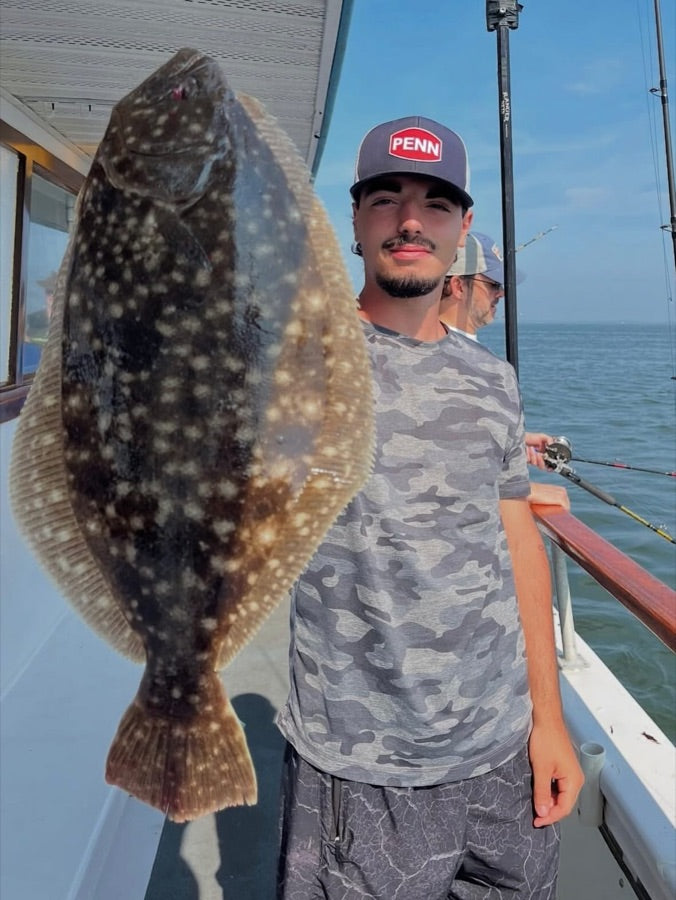 Angler holding a large fluke on a charter boat