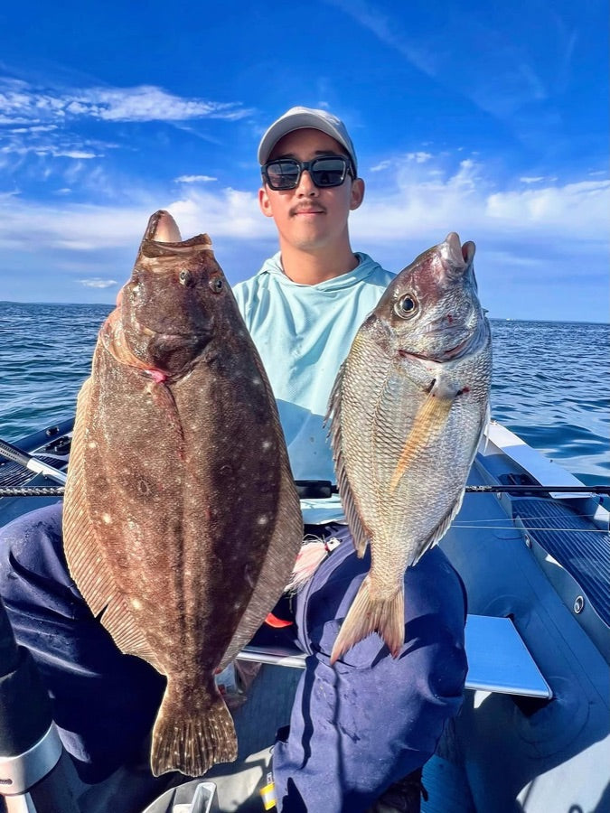 Angler holding a fluke and a porgy on a boat